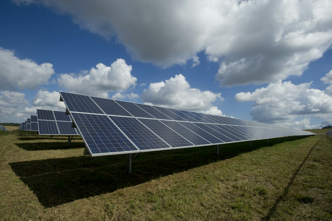 Painéis solares em campo aberto sob céu azul